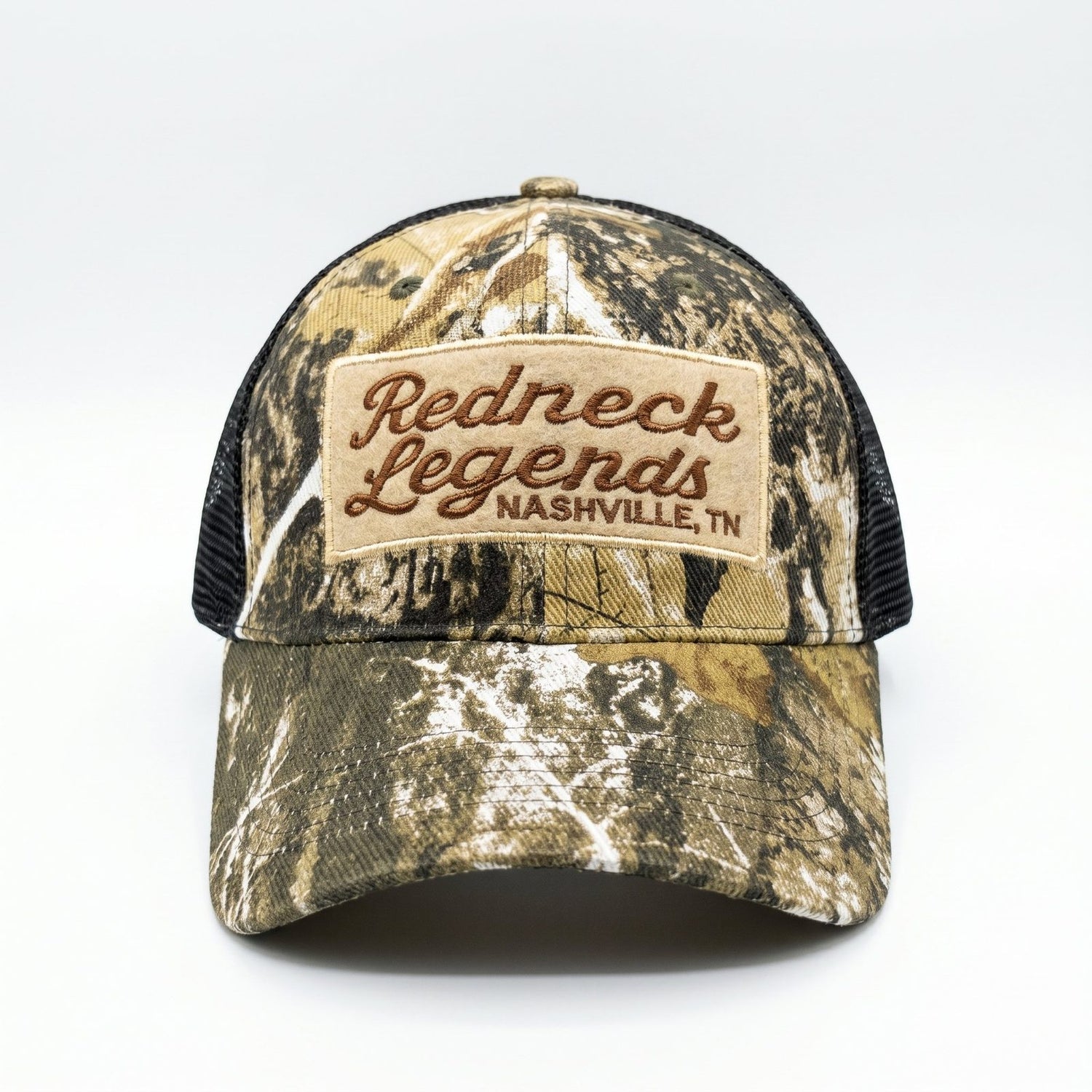 Camo Trucker Hat by Redneck Legends — front view of woodland tree-camo panels with an embroidered Redneck Legends Nashville TN patch and black mesh sides.