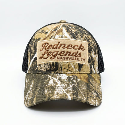 Camo Trucker Hat by Redneck Legends — front view of woodland tree-camo panels with an embroidered Redneck Legends Nashville TN patch and black mesh sides.