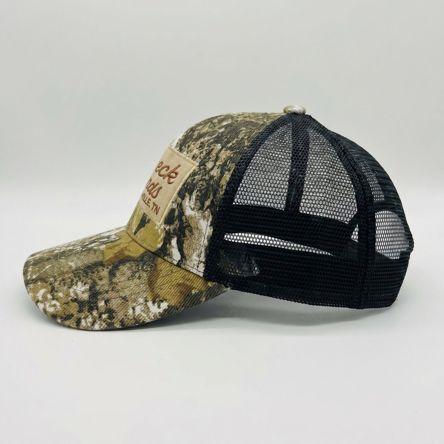 Camo Trucker Hat by Redneck Legends — side profile showing the camo crown and bill with a black mesh back panel.