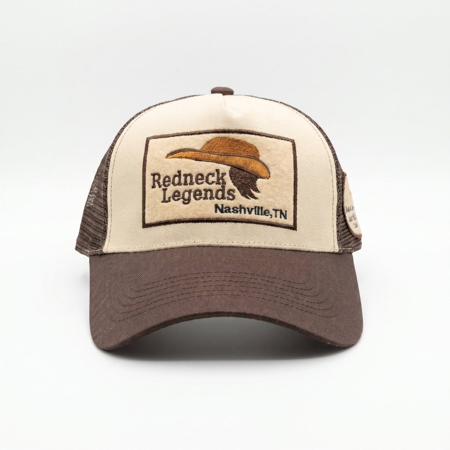 Redneck Legends Cream &amp; Brown Trucker Hat — front view, cream crown with embroidered cowboy hat and mullet logo patch, brown brim