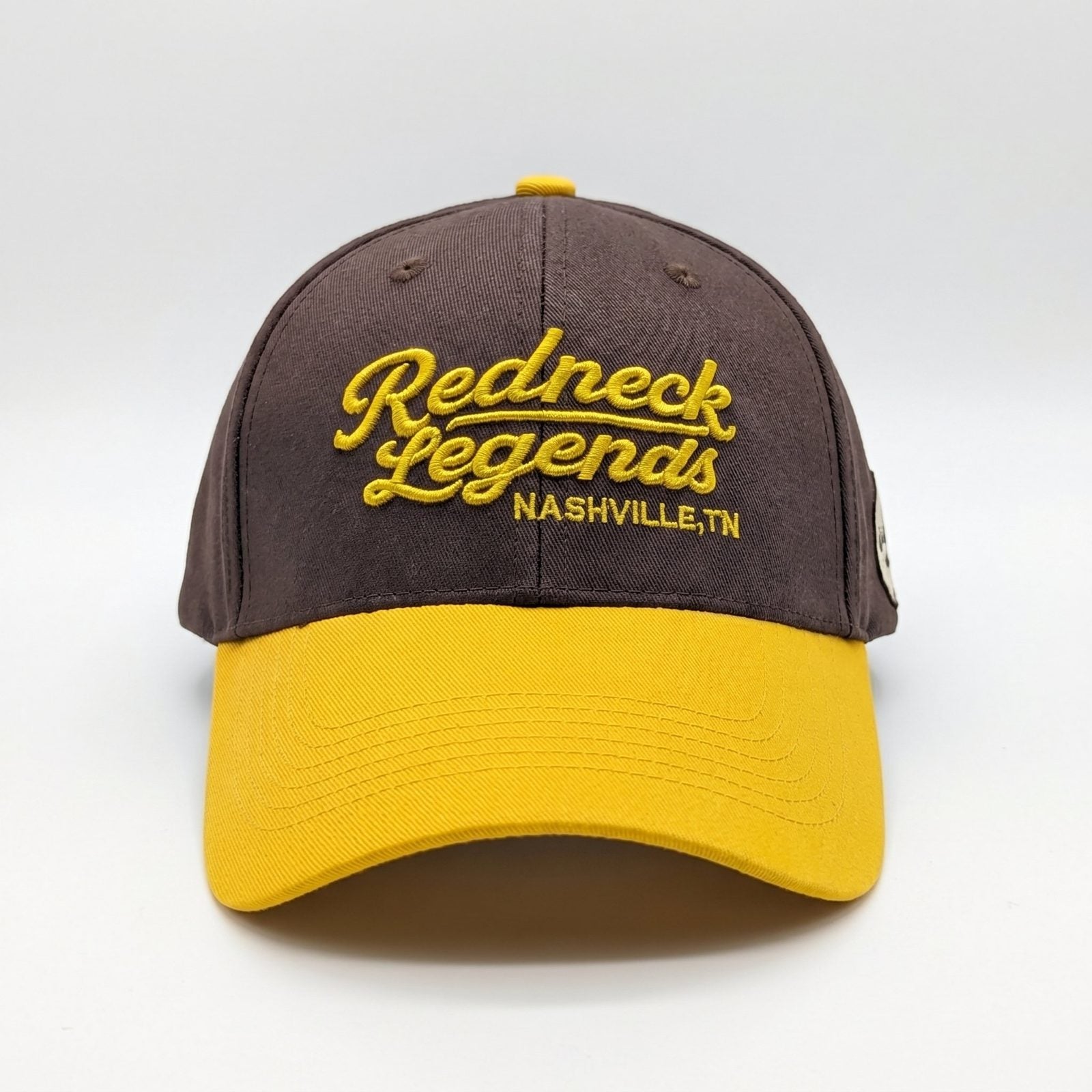Brown &amp; Gold Snapback Cap by Redneck Legends — brown crown with raised gold "Redneck Legends Nashville TN" embroidery and a golden-yellow curved bill.