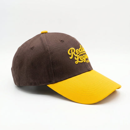 Brown &amp; Gold Snapback Cap by Redneck Legends — side view of the structured brown crown and golden-yellow curved bill.